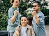Os ex-líderes do desenvolvimento do jogo Tekken, Yonemori Ikeda e Harada, levantam os punhos para uma foto