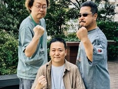Os ex-líderes do desenvolvimento do jogo Tekken, Yonemori Ikeda e Harada, levantam os punhos para uma foto