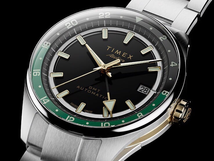 Vista em ângulo do Timex Atelier GMT Première M1a, mostrando seu mostrador preto, anel GMT verde, coroa em tom dourado e pulseira de aço inoxidável.