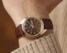 Timex Q 1978 Day and Date com mostrador fumé castanho e caixa em tom dourado, apresentado num pulso com uma bracelete de couro castanho.