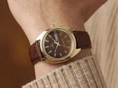 Timex Q 1978 Day and Date com mostrador fumé castanho e caixa em tom dourado, apresentado num pulso com uma bracelete de couro castanho.