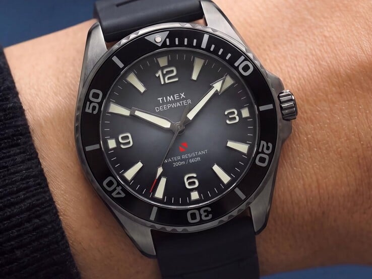 Relógio de mergulho Timex Deepwater Arctic 200 com mostrador degradê esfumaçado, luneta de cerâmica preta, marcadores de hora luminescentes e pulseira de borracha preta, mostrado em um pulso.