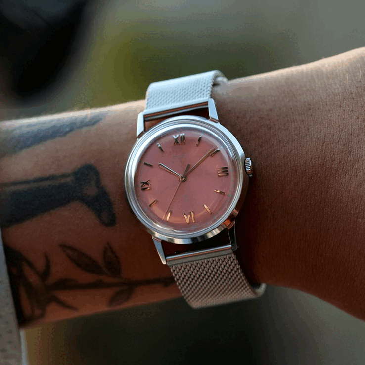 Pessoa usando o relógio Timex x Todd Snyder Marlin Mesh com mostrador salmão com efeito sunburst e pulseira de malha.