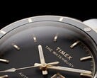 Close-up do relógio Timex Waterbury Heritage Automatic com mostrador preto, exibindo seus ponteiros facetados e luminosos, os marcadores de horas, o indicador de dia e data e a luneta preta.