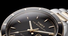 Close-up do relógio Timex Waterbury Heritage Automatic com mostrador preto, exibindo seus ponteiros facetados e luminosos, os marcadores de horas, o indicador de dia e data e a luneta preta.