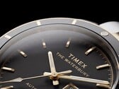 Close-up do relógio Timex Waterbury Heritage Automatic com mostrador preto, exibindo seus ponteiros facetados e luminosos, os marcadores de horas, o indicador de dia e data e a luneta preta.