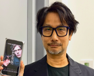 Hideo Kojima mostrando um pôster de Physint em seu celular