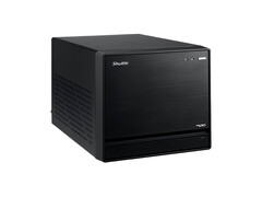 A imagem mostra uma visão frontal do Mini PC Shuttle XPC, que parece um cubo preto com um design minimalista. 