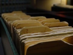 Uma fileira de pastas com argolas antigas em uma sala mal iluminada.