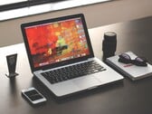 MacBook Pro sobre uma mesa escura ao lado de um smartphone, óculos e caderno