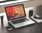 MacBook Pro sobre uma mesa escura ao lado de um smartphone, óculos e caderno
