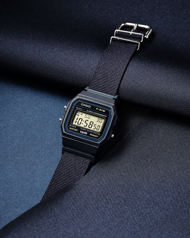 Casio F-91WF-2A com pulseira de tecido azul-marinho.