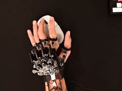 Um dispositivo de exoesqueleto DIY preso a uma mão enquanto se usa um mouse para jogos (Fonte da imagem: Basically Homeless/YouTube)