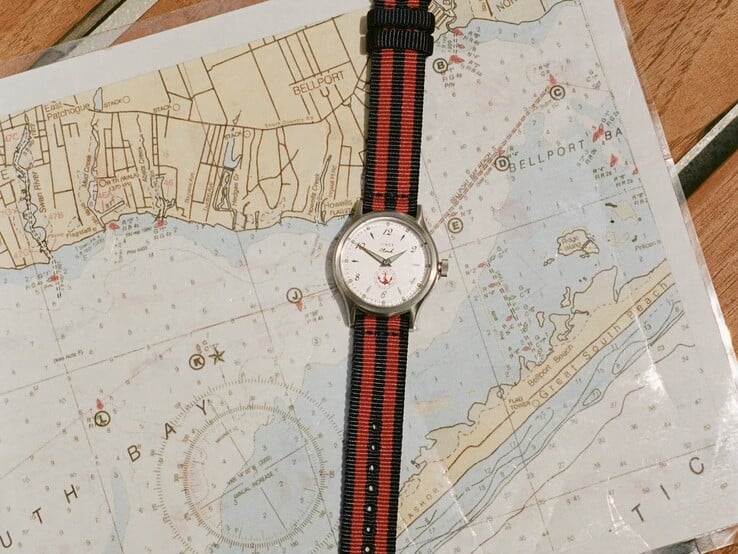 Relógio Noah x Timex MK1 Anchor com pulseira de tecido listrado em azul-marinho e vermelho, apoiado sobre uma carta náutica.
