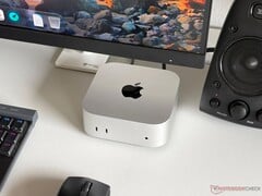 Um Mac mini com chip Apple M6 sobre uma mesa em uma configuração para jogos, com monitor, teclado, mouse e alto-falante.