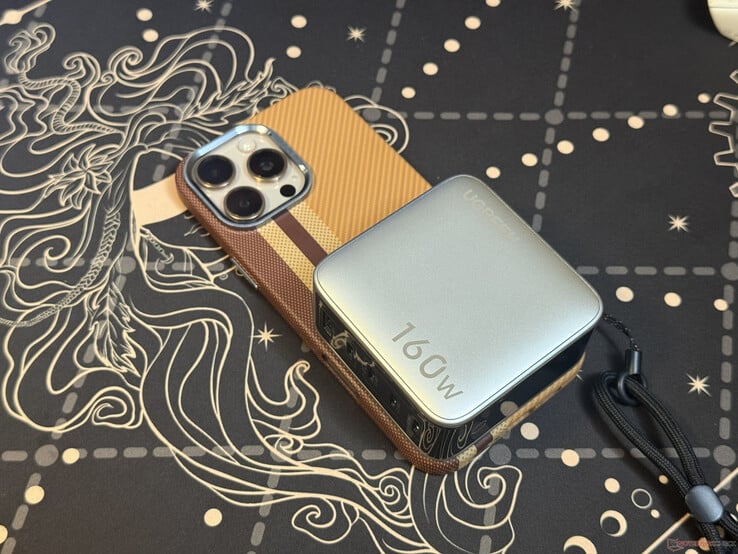 O carregador Ugreen Nexode Pro de 160 W com cinco portas, colocado sobre o iPhone 16 Pro Max