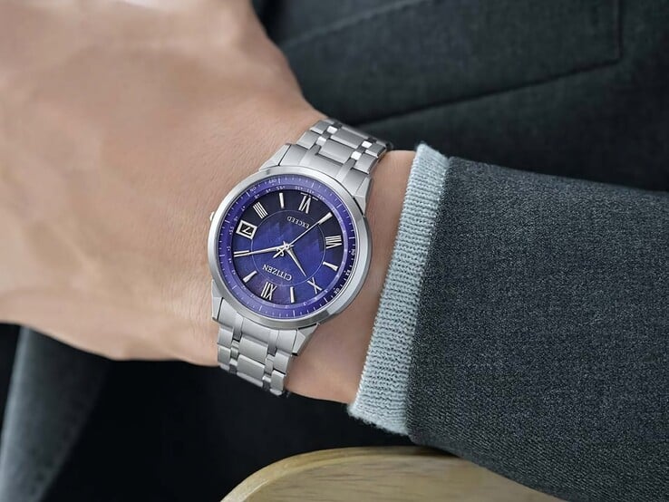 O Citizen Exceed CB1140-79L usado no pulso, mostrando seu mostrador azul, caixa em tom prateado e pulseira integrada de titânio junto a uma jaqueta escura.