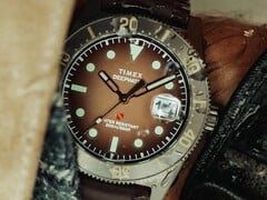 Relógio de mergulho Huckberry x Timex Deepwater Reef 200 com mostrador marrom, caixa em aço inoxidável, luneta preta e pulseira marrom combinando.