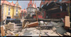 Esta cena de Overwatch 2 mostra um canto urbano devastado pela guerra, onde alvenaria desmoronada e fachadas destruídas cortam a arquitetura estilizada e limpa do mapa.