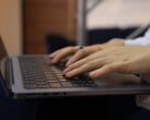 Mãos digitando no teclado de um laptop escuro
