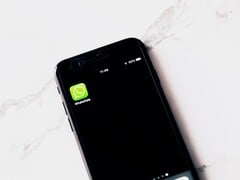 Smartphone sobre uma mesa branca exibindo o aplicativo WhatsApp