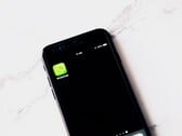 Smartphone sobre uma mesa branca exibindo o aplicativo WhatsApp
