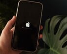 Uma mão segura um iPhone; o logotipo da Apple e uma barra de progresso estão iluminados na tela.