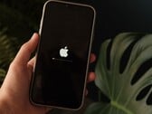 Uma mão segura um iPhone; o logotipo da Apple e uma barra de progresso estão iluminados na tela.