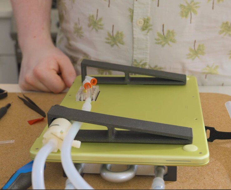 MacBook Neo modificado com bomba externa e configuração de tubulação para resfriamento líquido DIY