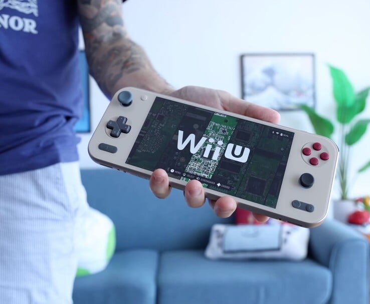 Russ, da Retro Game Corps, segurando o console portátil Ayaneo Pocket S2 que executa um emulador de Wii U, com o dispositivo mostrado em destaque em um ambiente de sala de estar. (Fonte da imagem: Retro Game Corps)