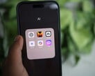 Uma mão segura um smartphone que exibe uma pasta chamada “AI” com aplicativos que incluem o Gemini, o ChatGPT e o Claude