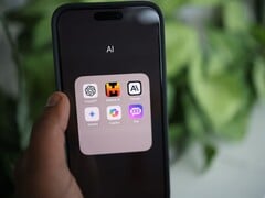 Uma mão segura um smartphone que exibe uma pasta chamada “AI” com aplicativos que incluem o Gemini, o ChatGPT e o Claude