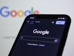 Smartphone mostrando a página de pesquisa do Google em frente a uma tela com o logotipo do Google