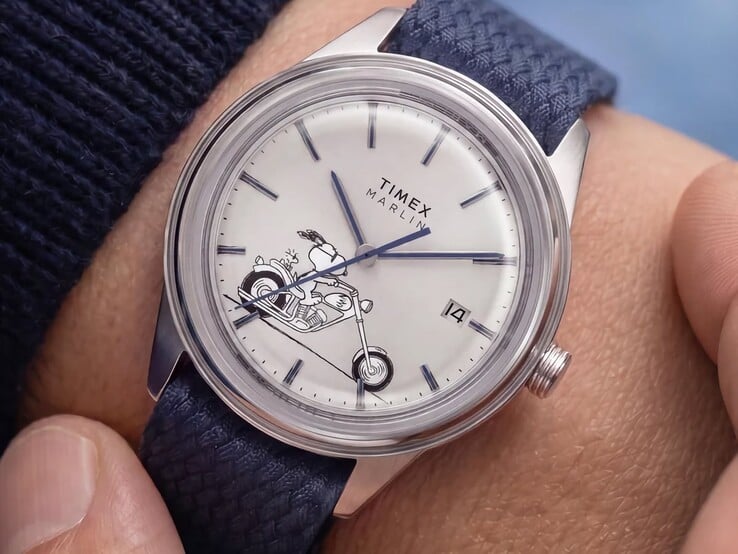 O relógio Peanuts x Timex Marlin Jet Automatic Easy Rider usado no pulso, mostrando o Snoopy pilotando uma motocicleta no mostrador branco-prateado, com marcadores e ponteiros azuis, e uma pulseira de tecido azul.