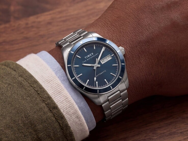 Relógio Timex Waterbury Heritage Automatic com mostrador em esmalte azul, usado no pulso, exibindo sua caixa na cor prata e pulseira de aço inoxidável.