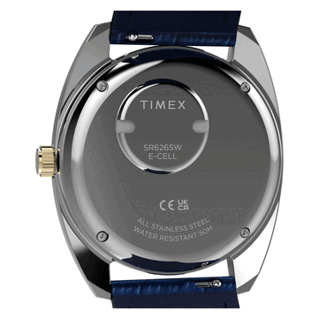 Vista traseira do Timex Q 1976 Day and Date em tom dourado, mostrando o fundo da caixa em aço inoxidável, o compartimento da bateria e a marcação de resistência à água até 50 metros.