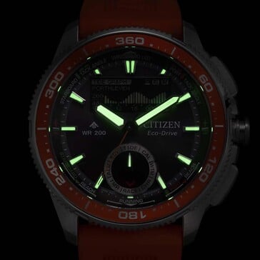 Foto do Citizen Promaster Wave Tracker JV3000-13E com lume em baixa luminosidade, mostrando ponteiros e marcadores de horas brilhantes em um fundo escuro.