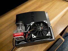 PlayStation 3 refrigerado a água personalizado com uma bomba SysCooling vermelha e um grande ventilador preto montado dentro do gabinete, colocado em uma mesa de madeira. (Fonte da imagem: Zac Builds via YouTube)
