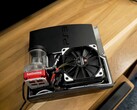 PlayStation 3 refrigerado a água personalizado com uma bomba SysCooling vermelha e um grande ventilador preto montado dentro do gabinete, colocado em uma mesa de madeira. (Fonte da imagem: Zac Builds via YouTube)