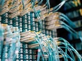 Cabos de fibra óptica azuis com conectores brancos conectados a um painel de conexões em um centro de dados