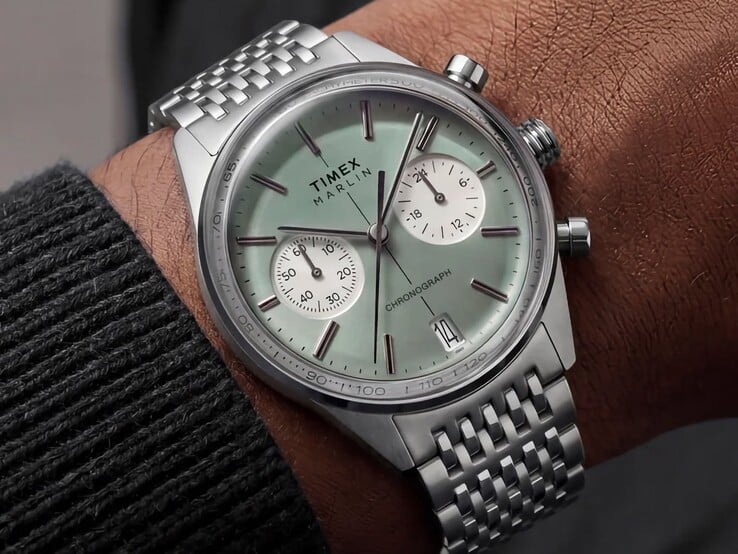 O relógio Timex Marlin Jet Chronograph, com mostrador verde-salva e pulseira de aço inoxidável, usado no pulso, exibindo seu cristal abaulado e o perfil arredondado da caixa, de estilo retrofuturista.