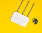 Roteador Wi-Fi branco com três antenas e uma fonte de alimentação sobre um fundo amarelo