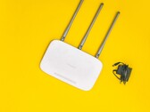 Roteador Wi-Fi branco com três antenas e uma fonte de alimentação sobre um fundo amarelo