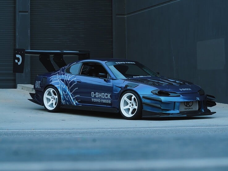 Carro de drift azul com gráficos da G-Shock e da Toyo Tires estacionado do lado de fora de um prédio industrial.