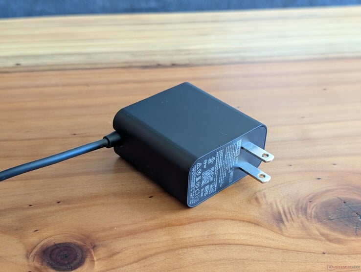 Adaptador CA USB-C de 65 W fornecido com o Lenovo Yoga Slim 7 14. Observe os pinos CA não retráteis e o cabo USB-C integrado na outra extremidade