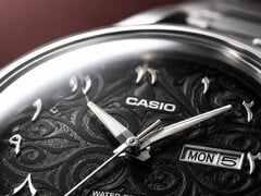 Grande plano do mostrador preto do Casio MTP-E735AR, com um intrincado padrão de arabescos, algarismos árabes orientais em relevo, ponteiros polidos em tom prateado e uma janela de dia e data às 3 horas.