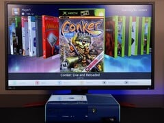 Um Xbox 360 azul modificado executando um painel de controle homebrew personalizado em um monitor, exibindo o jogo "Conker: Live and Reloaded" ao lado de outros títulos do Xbox e de emuladores. (Fonte da imagem: Modern Vintage Gamer no YouTube)