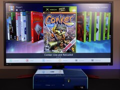  Um Xbox 360 azul modificado executando um painel de controle homebrew personalizado em um monitor, exibindo o jogo 