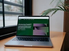 Laptop sobre uma mesa junto a uma janela, com o site do OpenAI ChatGPT aberto na tela