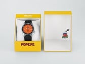 Relógio automático Seiko 5 Sports x Popeye HDB013, com mostrador laranja, ao lado de sua caixa de apresentação amarela de edição limitada.
